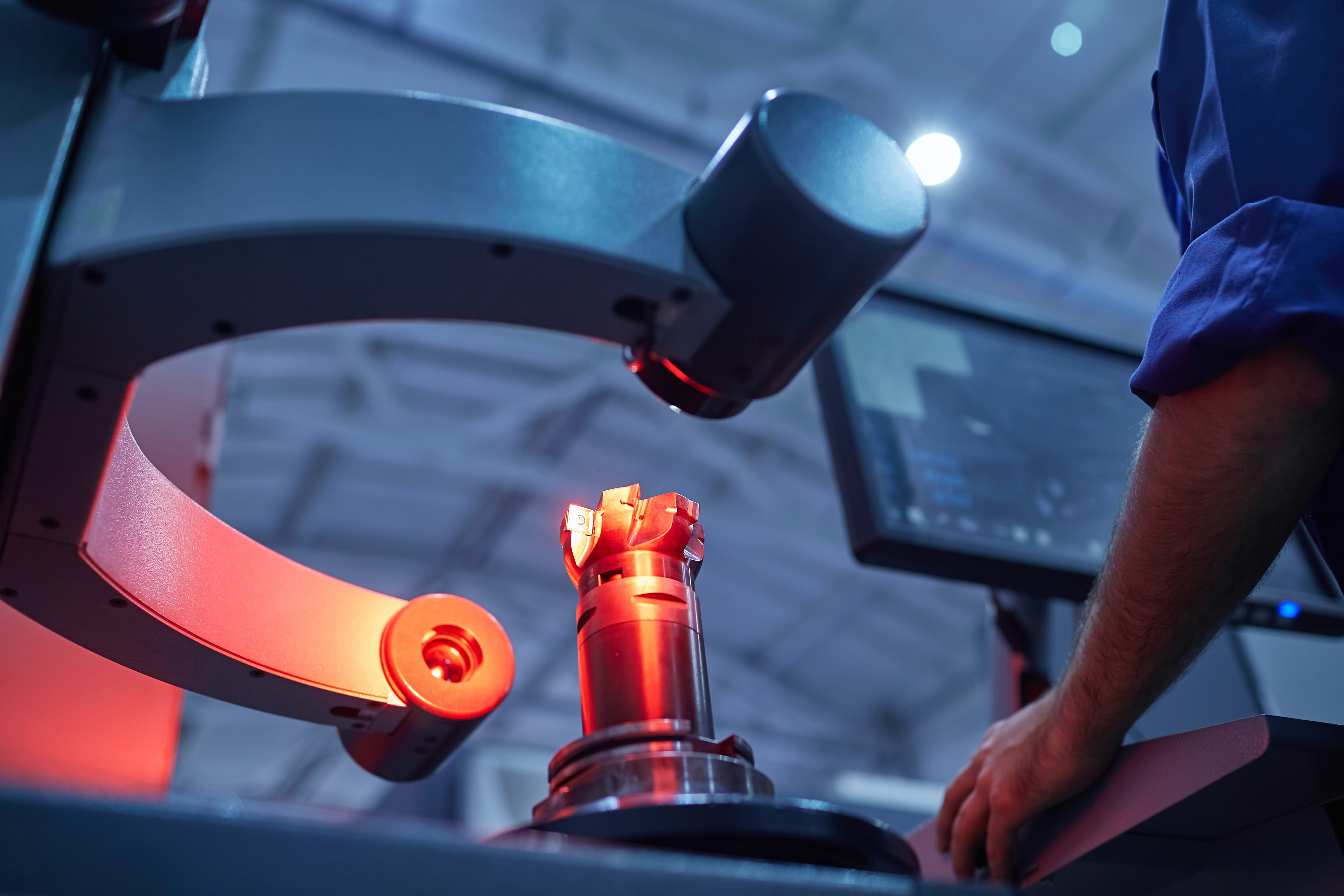 An engineer checking a machined part under an optical mea  ring system